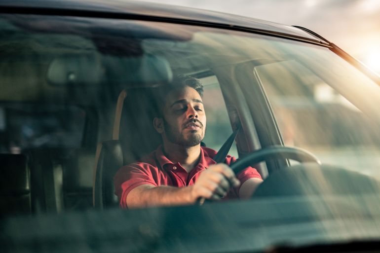 gettyimages-1211980101-1758383480 Middle Eastern man falling a sleep while driving a car.