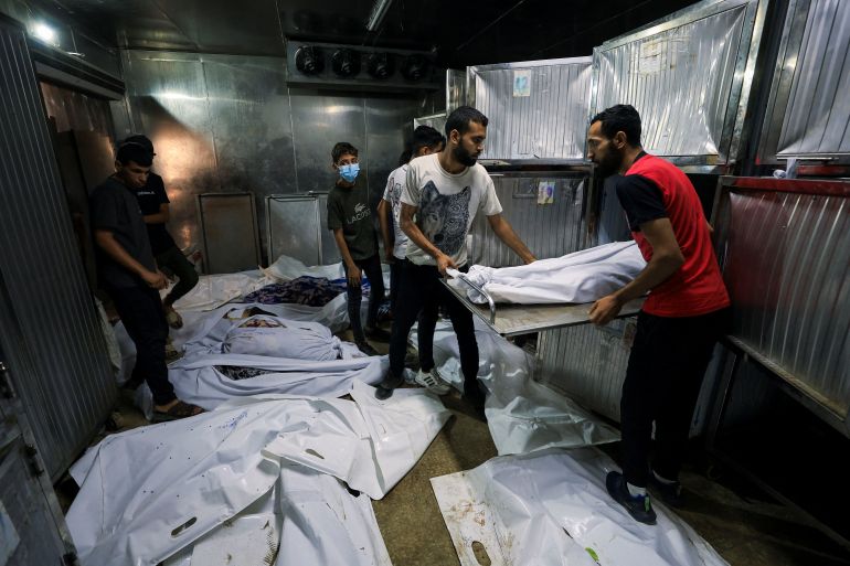 SENSITIVE MATERIAL. THIS IMAGE MAY OFFEND OR DISTURB People stand in the morgue near the bodies of victims on the day of the funeral of Palestinians killed by Israeli fire while trying to receive aid on Friday, and others killed in overnight strikes, according to medics, at Al-Shifa Hospital in Gaza City, September 6, 2025. REUTERS/Dawoud Abu Alkas