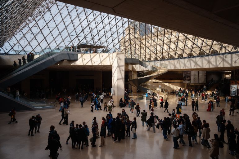 (FILES) Visitors walk under the Louvre Pyramid designed by Ieoh Ming Pei at the Louvre Museum in Paris on January 23, 2025. France's Culture Minister Rachida Dati on October 19, 2025 reported a theft at the Louvre in Paris, as the world-renowned museum said it was closing for the day. A robbery took place this morning at the opening of the Louvre Museum, she wrote on X. The Louvre said it was closing for the day for exceptional reasons, without providing further details on what had been stolen. (Photo by Dimitar DILKOFF / AFP) / RESTRICTED TO EDITORIAL USE - MANDATORY MENTION OF THE ARTIST UPON PUBLICATION - TO ILLUSTRATE THE EVENT AS SPECIFIED IN THE CAPTION