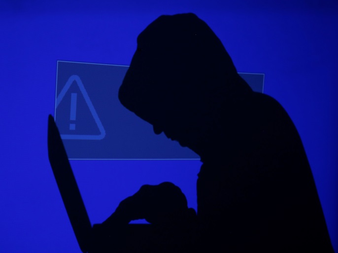 A hooded man holds a laptop computer as blue screen with an exclamation mark is projected on him in this illustration picture taken on May 13, 2017. Capitalizing on spying tools believed to have been developed by the U.S. National Security Agency, hackers staged a cyber assault with a self-spreading malware that has infected tens of thousands of computers in nearly 100 countries. REUTERS/Kacper Pempel/Illustration