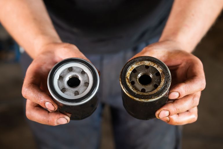 546ytrg-1761753026 An auto mechanic holds a new and used oil filter. by Михаил Решетников ادوبي ستوك