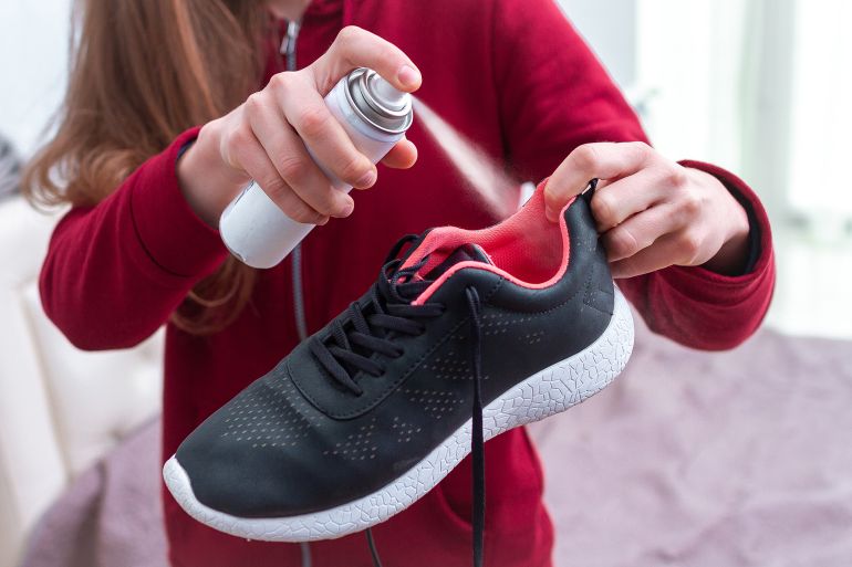 56d8bad8b9d982d981d8a8d984d8ba-1759416587 A young woman spraying deodorant on sweaty running shoes for eliminate unpleasant, bad smell. Shoe shine and care. Sport footwear needs in cleaning and odor removal.