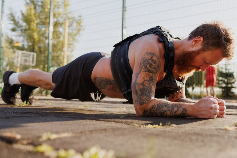 56uytfgh-1759324861 Tattooed sportsman doing plank in park in morning