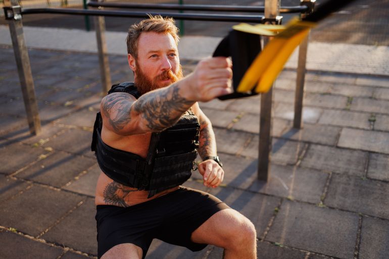 5yghj67-1759324868 Adult sportsman training with suspension straps at outdoor gym