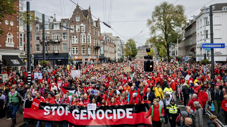 afp_68e27cbfd89c-1759673535 TOPSHOT - Demonstrators including some holding a banner reading "Stop Genocide" take part in a "Red Line" protest demanding "government action to stop the genocide in Gaza" in Amsterdam on October 5, 2025.