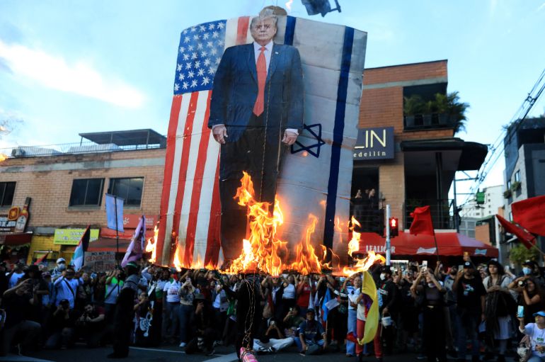 Demonstrators set fire to a sign depicting US President Donald Trump with the US and Israeli flags during a march in Medellin, Colombia on October 7, 2025, on the second anniversary of the deadly Hamas-led attack on Israel which sparked a retaliatory offensive in Gaza.