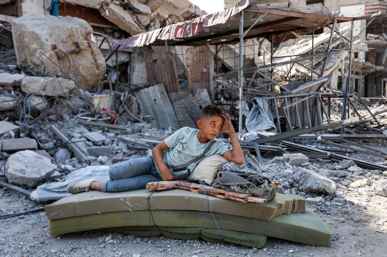 TOPSHOT - A boy lies on several foam mattresses by rubble outside a destroyed building in the centre of Khan Yunis in the southern Gaza Strip on October 10, 2025, as displaced people return to their homes after Israeli forces' withdrawal.