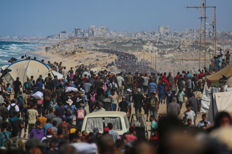 TOPSHOT - Palestinians walk along Al-Rashid road toward Gaza City from Nuseirat in the central Gaza Strip on October 10, 2025.