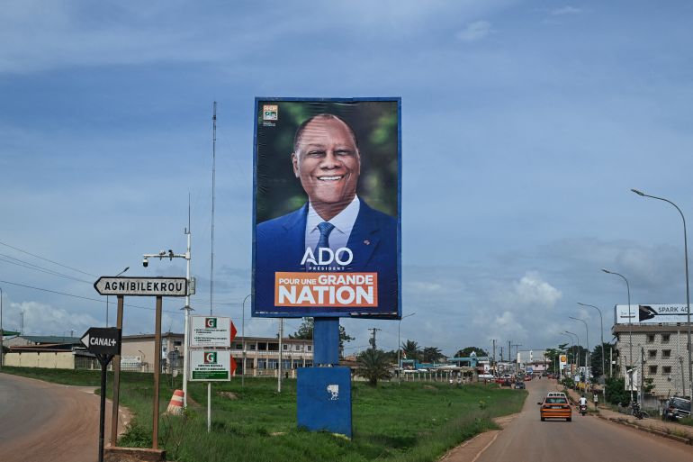afp_68ef6da32aa8-1760521635 Cars drive past a campaign billboard of Ivorian President and presidential candidate for Rally of Houphouetists for Democracy and Peace (RHDP) Alassane Ouattara in the city of Abengourou, eastern Ivory Coast, on October 14, 2025. (Photo by Issouf SANOGO / AFP)