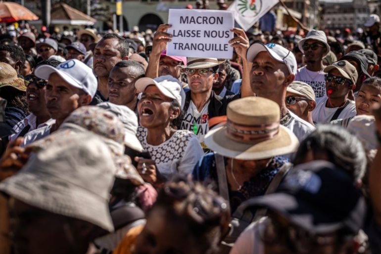 afp_68ef7e1bbd34-1760525851 A protester holds a banner critical of France’s President Emmanuel Macron as residents gather for a civil society rally demanding the resignation of Madagascar’s President Andry Rajoelina in Antananarivo, on October 14, 2025.