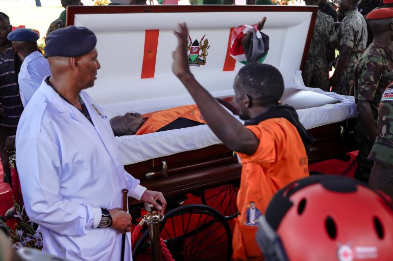 afp_68f26bbbbedc-1760717755 A mourner waves next to the body of Kenya’s opposition leader and former Prime Minister Raila Odinga lying in state for public viewing during his State Funeral at Nyayo Stadium in Nairobi on October 17, 2025.