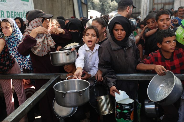 afp_68f49455cc5f-1760859221 Palestinians gather to receive food portions from a charity kitchen in the Nuseirat refugee camp, located in the central Gaza Strip, on October 15, 2025, two days after a ceasefire came into effect.