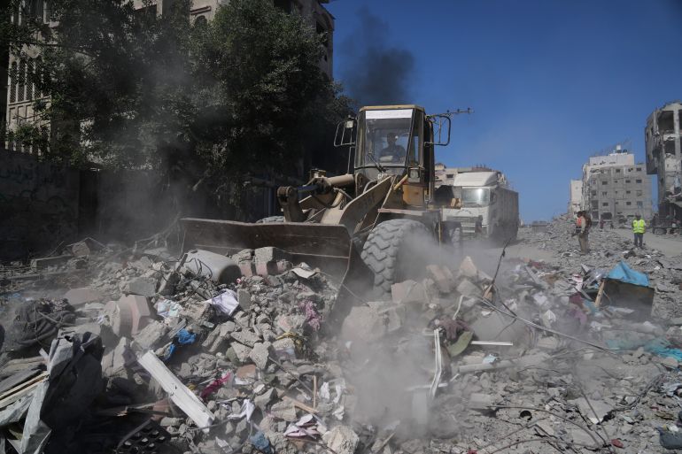 A Palestinian operates a mechanical shovel to clear debris from the heavily damaged Al-Jalaa Street in Gaza City, Saturday, Oct. 11, 2025, after Israel and Hamas agreed to a pause in their war and the release of the remaining hostages. (AP Photo/Abdel Kareem Hana)