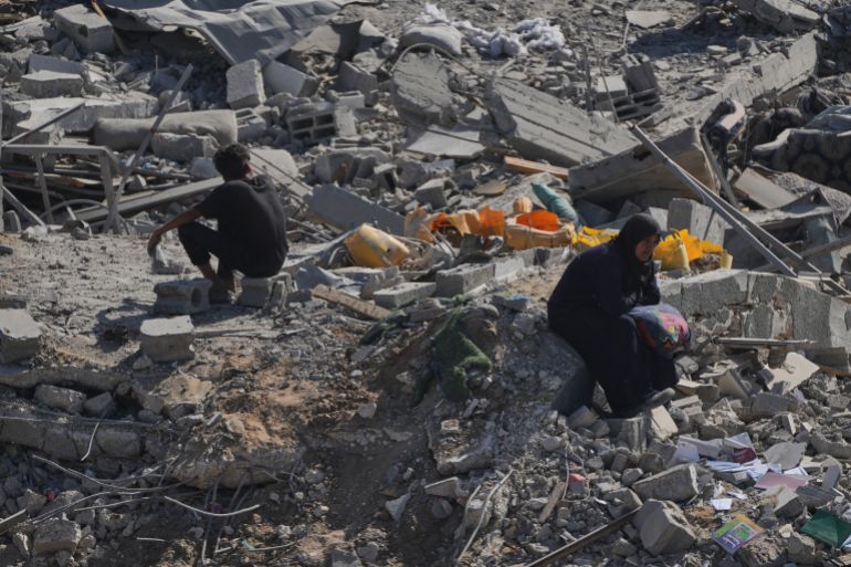 A displaced Palestinian woman sits on the remains of a destroyed building in the heavily damaged Sheikh Radwan neighborhood in Gaza City, Saturday, Oct. 11, 2025, after Israel and Hamas agreed to a pause in their war and the release of the remaining hostages. (AP Photo/Abdel Kareem Hana)