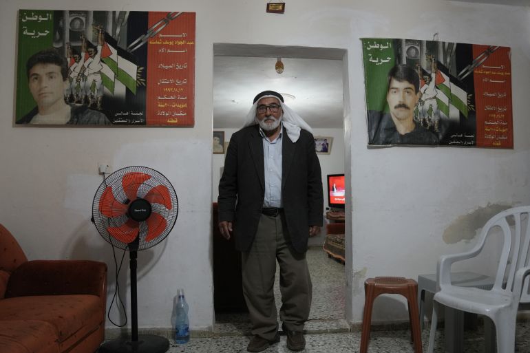 Yousef Shamasneh, 83, passes by posters of his two imprisoned sons, Abdel Jawad, right, and Mohammad, at his home in the West Bank village of Qatanna, west of Jerusalem, Friday, Oct. 10, 2025. (AP Photo/Mahmoud Illean)