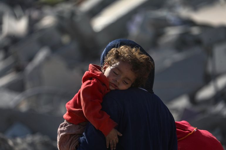 epa12447232 A Palestinian mother carrying her child walks among the rubble of destroyed buildings amid a ceasefire between Israel and Hamas in Gaza City, 11 October 2025. US President Donald Trump announced that Israel and Hamas have agreed to the first phase of a Gaza peace plan. The deal involves the release of Israeli hostages and Palestinian prisoners, the withdrawal of Israeli forces, and the delivery of humanitarian aid to Gaza. EPA/MOHAMMED SABER