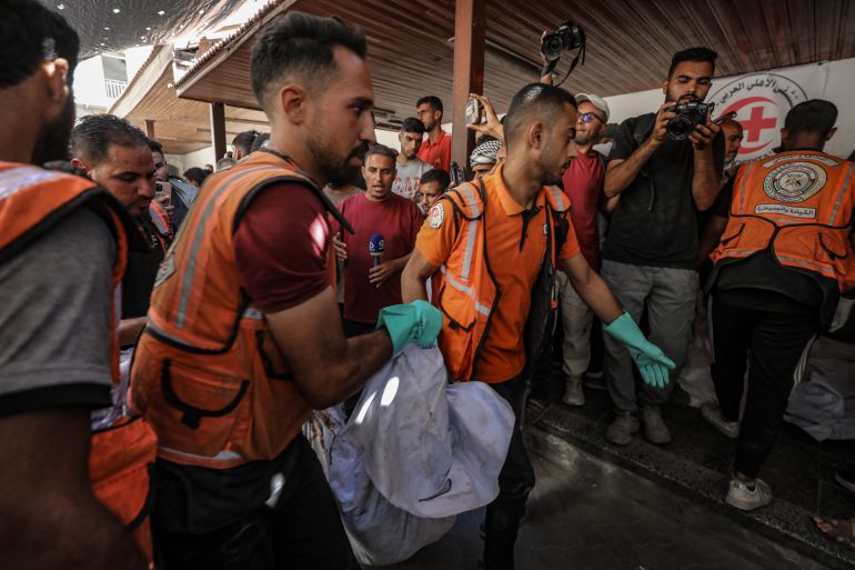 epa_68f4923c08c1-1760858684 epa12462102 Palestinian civil defense workers carry the body of a member of the Abu Shaban family at Al Ahli Baptist Hospital in Gaza City, 18 October 2025. At least eleven members of the Abu Shaban family were killed a day earlier when their car was hit by an Israeli army strike in the Al Zaitun neighbourhood, east of Gaza City. EPA/MOHAMMED SABER