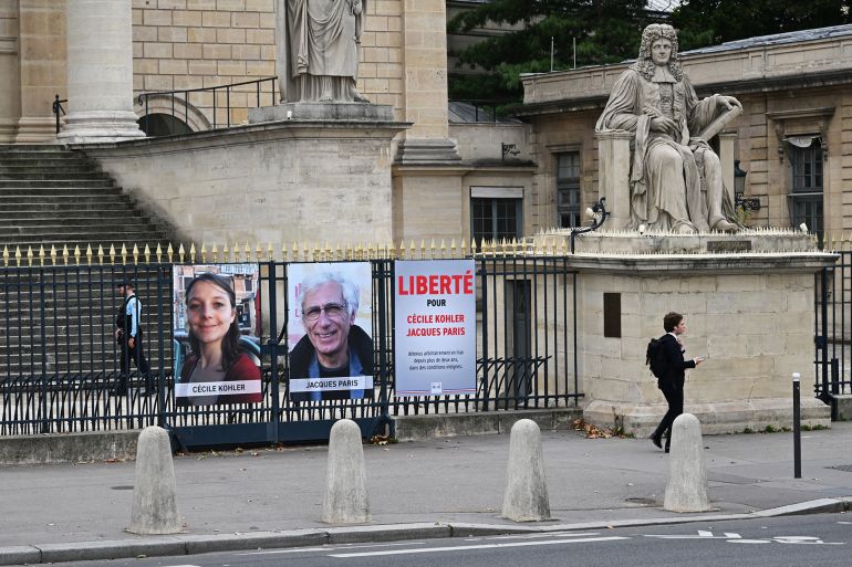 iraaaaan-2-1760457351 This photograph shows portrait placards of Cecile Kohler and Jacques Paris, two French citizens detained in Iran, set up on a fence of the French National Assembly, in Paris on October 6, 2025. Two French nationals, Cécile Kohler and Jacques Paris, accused notably of espionage on behalf of Israel, are detained in Iran and face the death penalty. They were arrested on May 7, 2022, on the last day of a tourist trip. (Photo by Martin LELIEVRE / AFP)