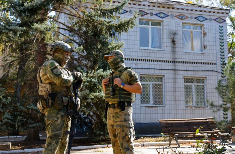 Russian service members stand guard outside a school where volunteers deliver humanitarian aid in the course of Russia-Ukraine conflict in the town of Kurakhove, in the Donetsk region, a Russian-controlled area of Ukraine, September 23, 2025. REUTERS/Alexander Ermochenko