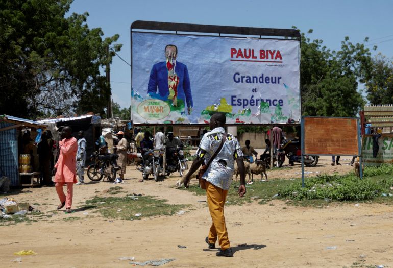 reuters_68dfd817-1759500311 FILE PHOTO: A man walks past a damaged electoral billboard of the presidential candidate Paul Biya in Yagoua, Cameroon September 30, 2025. REUTERS/Desire Danga Essigue/File Photo