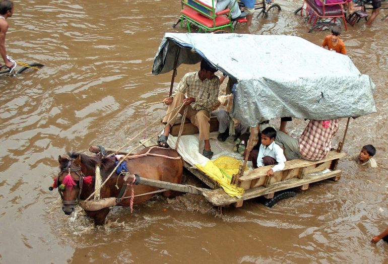 FILE PHOTO: People commute on a flooded road after heavy monsoon rain in the northern Indian city of Mathura August 5, 2008. REUTERS/K. K. Arora (INDIA)/File Photo