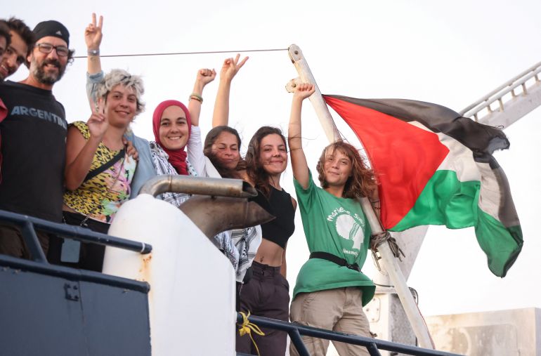 Greta Thunberg and other crew members flash victory signs from their ship, part of the Global Sumud Flotilla aiming to reach Gaza and break Israel's naval blockade, as they sail off Crete island, Greece, September 25, 2025. REUTERS/Stefanos Rapanis