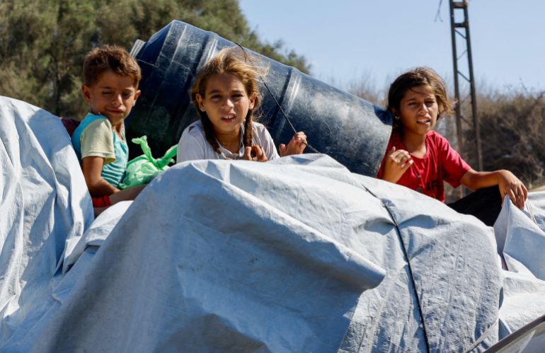 Children sit among belongings as Palestinians, who were displaced to the southern part of Gaza at Israel's order during the war, return to the north after a ceasefire between Israel and Hamas in Gaza went into effect, in the central Gaza Strip, October 10, 2025. REUTERS/Mahmoud Issa