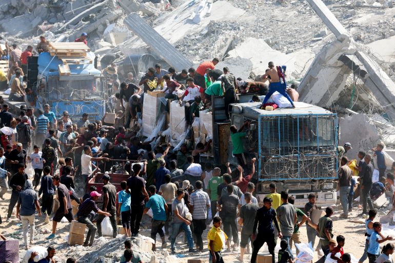 Palestinians collect aid supplies from trucks that entered Gaza, amid a ceasefire between Israel and Hamas, in Khan Younis, in the southern Gaza Strip October 12, 2025. REUTERS/Ramadan Abed
