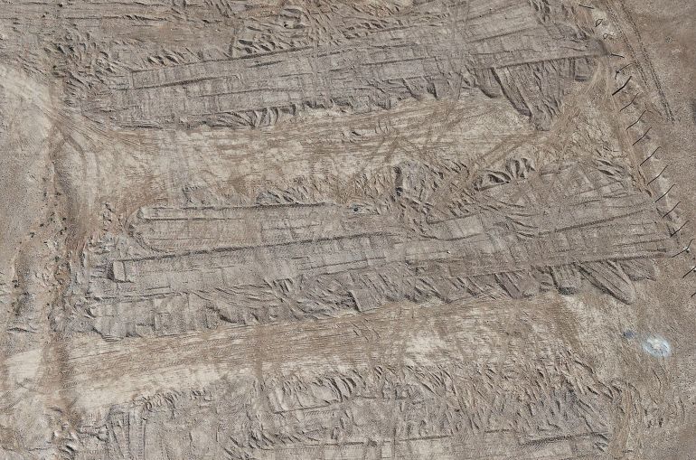 A drone view of imprints, made by bulldozer tracks, on the soil covering a burial trench of a mass grave in the eastern Syrian desert near the town of Dhumair, February 27, 2025. A Reuters investigation found that the Assad government secretly trucked thousands of bodies there from an exposed mass grave in the Damascus suburb of Qutayfah from 2019-2021. REUTERS/Khalil Ashawi