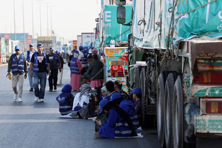 reuters_68f0f277-1760621175 Egyptian volunteers rest and sit next to trucks loaded with humanitarian aid from Egypt's National Alliance For Civil Development Work (NACDW) as they are on their way to the Rafah border crossing to enter Gaza, after a ceasefire between Israel and Hamas in Gaza went into effect, on the Cairo-Ismailia desert road, in Egypt, October 16, 2025. REUTERS/Amr Abdallah Dalsh TPX IMAGES OF THE DAY