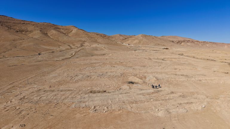 reuters_68f2638b-1760715659 Four people walk through the desert mass grave created under the Assad government near the town of Dhumair, Syria, February 27, 2025. A Reuters investigation found that the Assad government secretly trucked thousands of bodies to the site. REUTERS/Khalil Ashawi To match Special Report SYRIA-SECURITY/MASS GRAVES