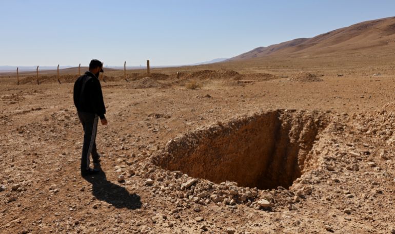 reuters_68f2639d-1760715677 Ahmed Ghazal, a Syrian mechanic, approaches a hole he said was intended to be a burial trench in the secret mass grave created by the Assad government near the town of Dhumair, Syria, February 27, 2025. He was once called to the site for an urgent repair to a dump truck carrying boides that had broken down. REUTERS/Khalil Ashawi To match Special Report SYRIA-SECURITY/MASS GRAVES