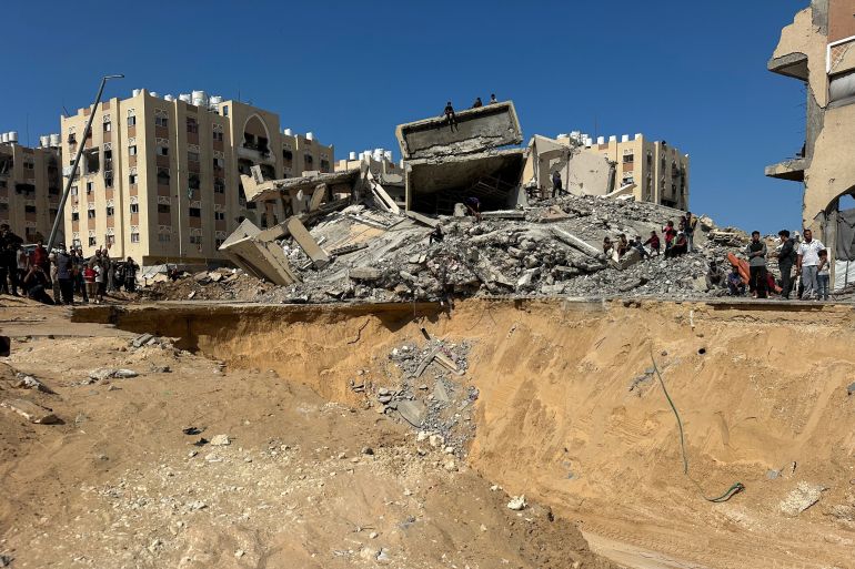 reuters_68f4a3e0-1760863200 Palestinians gather near a site where searches are underway for the bodies of hostages killed after being seized by Hamas during the October 7, 2023 attack, amid a ceasefire between Israel and Hamas, in Khan Younis, southern Gaza Strip, October 17, 2025. REUTERS/Stringer
