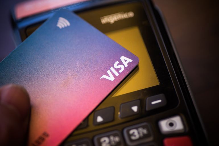 Bucharest, ROMANIA - May 17, 2021: Illustrative editorial concept image of a person holding a VISA card near a POS terminal. ; Shutterstock ID 1974915233; purchase_order: aj; job: ; client: ; other: