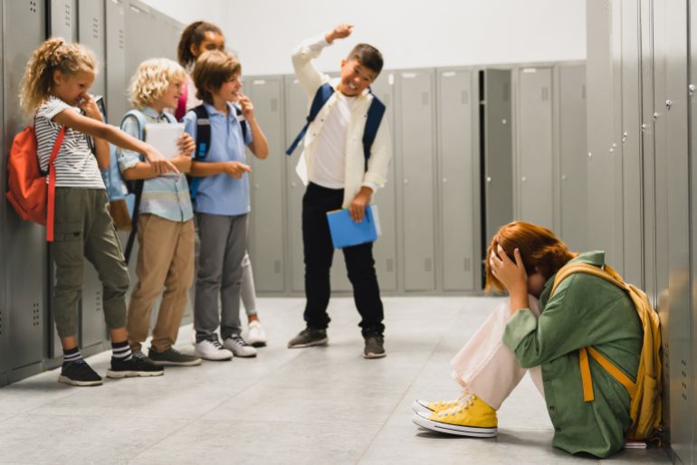 shutterstock_2108575589-1730977694 Angry cruel teenagers laughing at their classmate. Elementary school age bullying at school. Social inequality ...