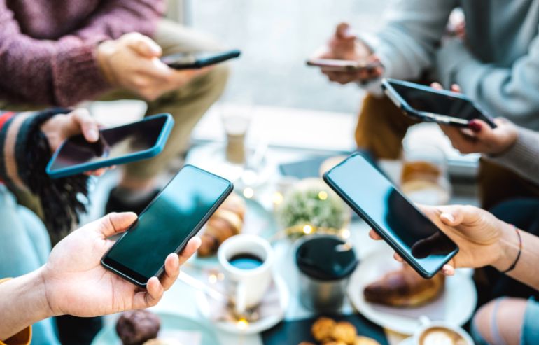 shutterstock_2219580449-1759229608 Friends group having fun using mobile smart phone chat - Detail of people hands phubbing content on social media network with smartphone - Genz technology concept with milenials online - Bright filter
