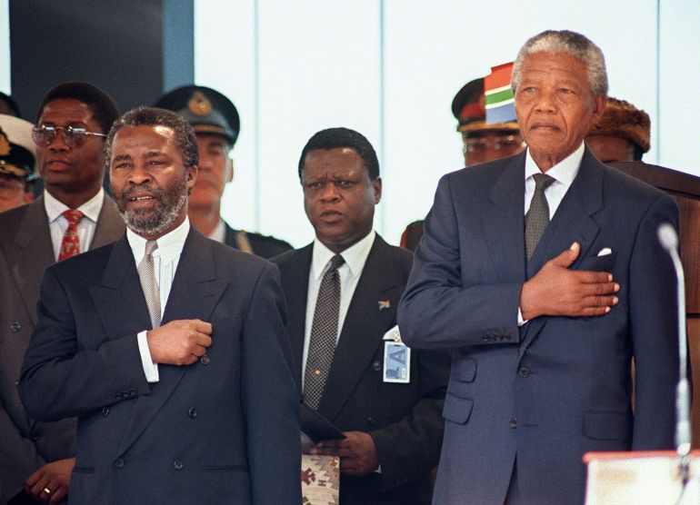South Africa's new President Nelson Mandela (R) stands at attention as the national anthem is played during his inauguration at the Union Building in Pretoria 10 May 1994. Pictured on his right, new Vice-President Thabo Mbeki. AFP PHOTO WALTER DHLADHLA (Photo by WALTER DHLADHLA / AFP) (Photo by WALTER DHLADHLA/AFP via Getty Images)