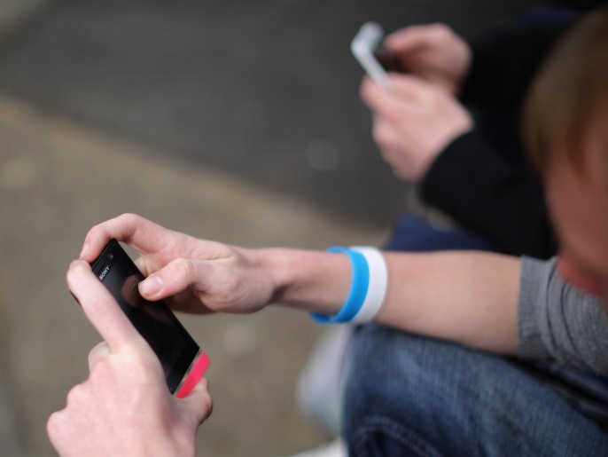 CORBY, ENGLAND - APRIL 24: Two youths send text messages on their smart phones in Corby, Northamptonshire, the youth unemployment capital of Britain, on April 24, 2013 in Corby, England. A recent study pin pointed Corby as Britain's youth unemployment capital. The study by education specialists Ambitious Minds found that youth unemployment was 11% rising from 4% in 2007. Corby in Northamptonshire was built around its steel industry in the 1930's. The steel works clos