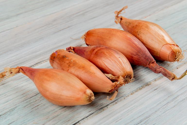 Side view of shallots on wooden background فري بيك