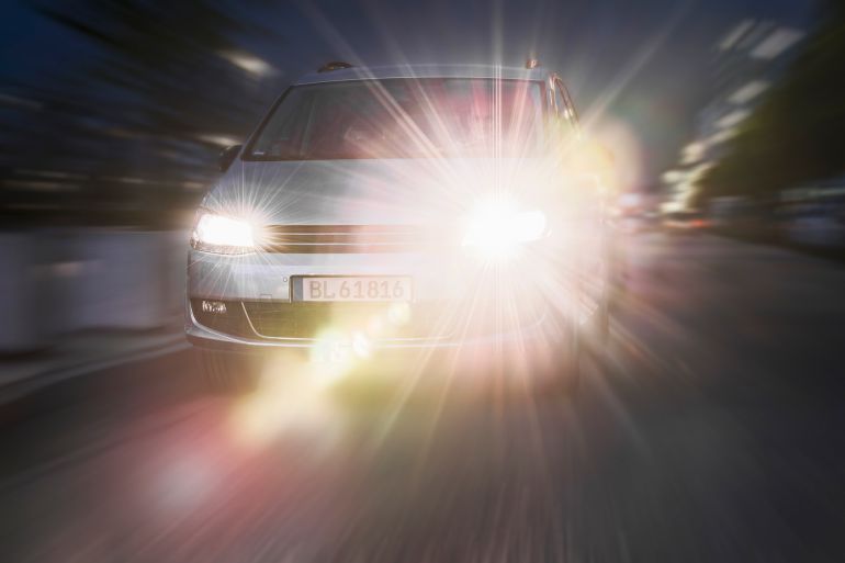 Car driving down street, headlights on