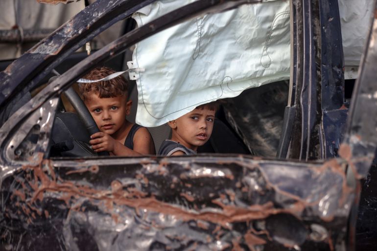 Displaced Palestinian children play inside a destroyed car in Deir al-Balah, Gaza Strip, on September 28, 2025. (Photo by Majdi Fathi/NurPhoto via Getty Images)