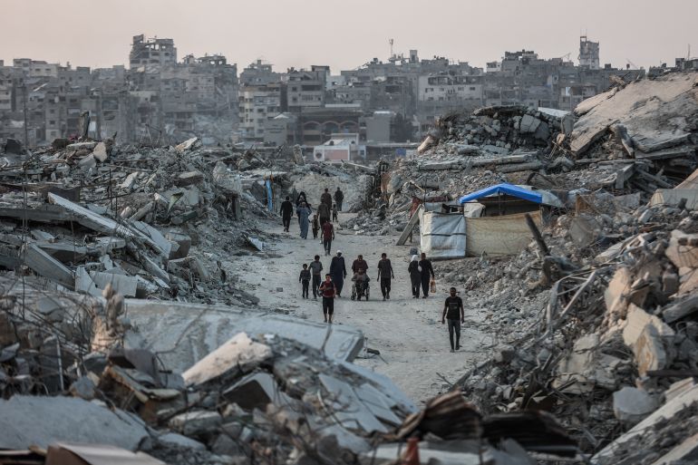 Palestinians walk amid the rubble of destroyed buildings in Jabalia, in the northern Gaza Strip, on November 7, 2025.