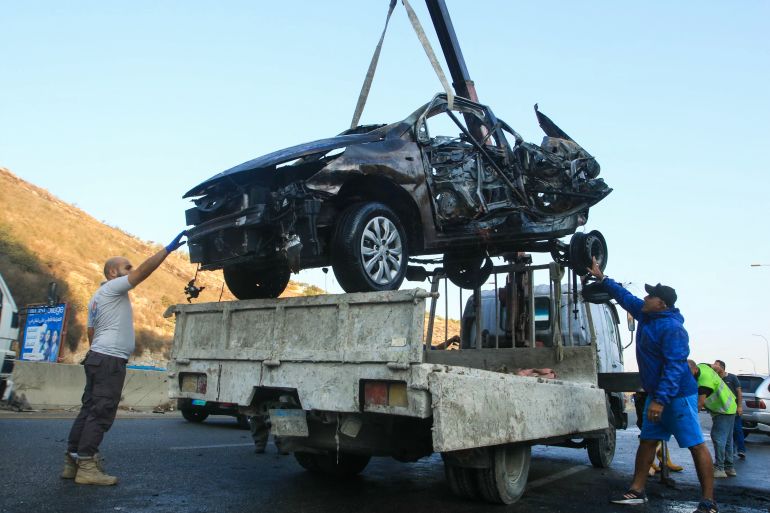 TOPSHOT - Workers remove the wreckage of a car targeted by an Israeli drone strike in the southern Lebanese village of Baissariyeh on November 10, 2025.