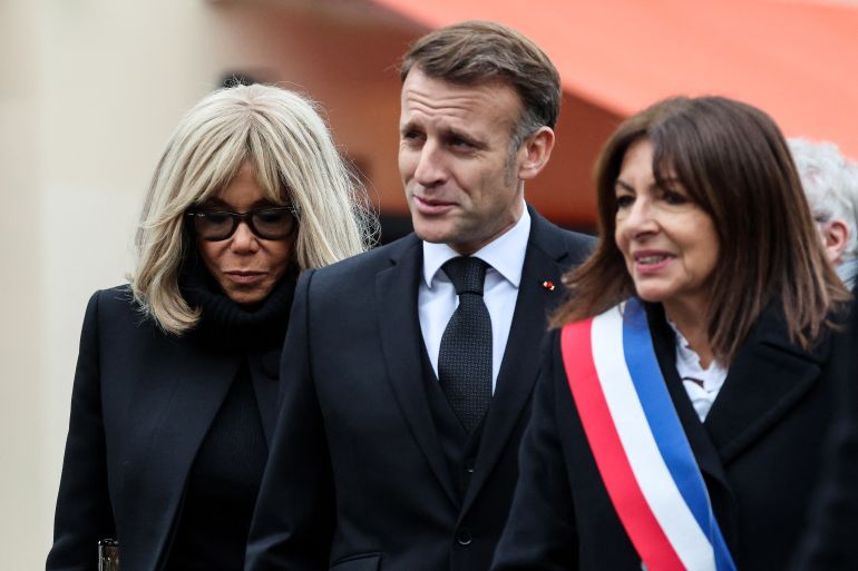 afp_6915c12d4d60-1763033389 France's President Emmanuel Macron (C), French President's wife Brigitte Macron (L) and Paris' mayor Anne Hidalgo arrive to pay tribute to victims at the intersection of of Bichat and Alibert streets near "Le Petit Cambodge" and "Le Carillon" in Paris on November 13, 2025, during ceremonies across Paris marking a decade since the terror attacks of November 13, 2015 in which 130 civilians were killed. (Photo by Ludovic MARIN / POOL / AFP)