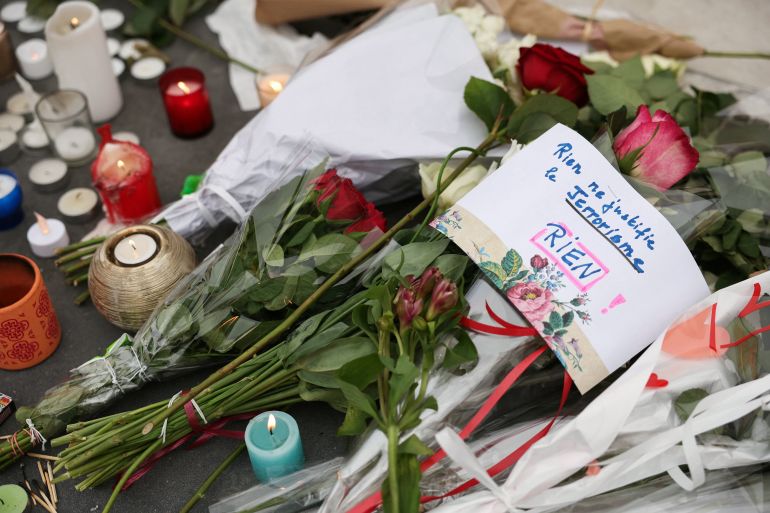 afp_6915c1aa1c38-1763033514 This photograph shows bouquets of flowers and a sign reading "Nothing justify terrorism, nothing" at a makeshift memorial at the Place de la Republique in Paris on November 13, 2025 during the anniversary marking a decade since the terror attacks of November 13, 2015 in which 130 civilians were killed. (Photo by Thomas SAMSON / AFP)