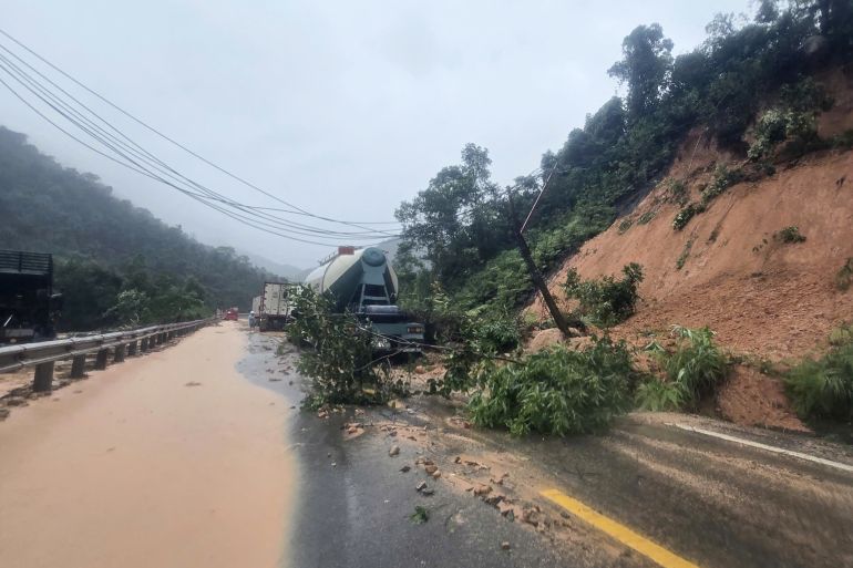 afp_691efae17fb4-1763637985 This photo taken and released by Vietnam News Agency (VNA) on November 17, 2025 shows vehicles stuck on a damaged road following landslides triggered by heavy rain, near the location where a passenger bus was submerged by falling soil and rock on Khanh Le Pass in Khanh Hoa province.