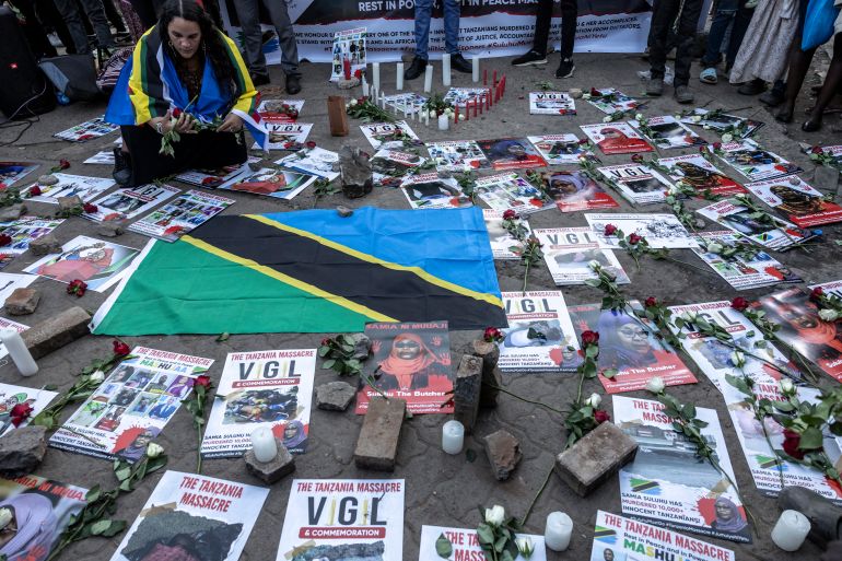 afp_6922eb5d96fb-1763896157 An activist places flowers next to the Tanzanian flag during a memorial vigil to honour Tanzanians killed in post-election unrest, in Nairobi, on November 20, 2025.