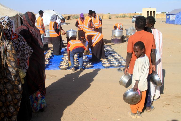 afp_6923895aa671-1763936602 Sudanese who fled El-Fasher queue to receive free meals at the Al-Afad camp for displaced people in the town of Al-Dabba, northern Sudan, on November 20, 2025.