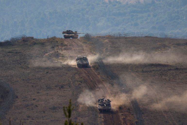 Israeli military tanks patrol close to a concrete wall along the border fence separating northern Israel from southern Lebanon on November 24, 2025.