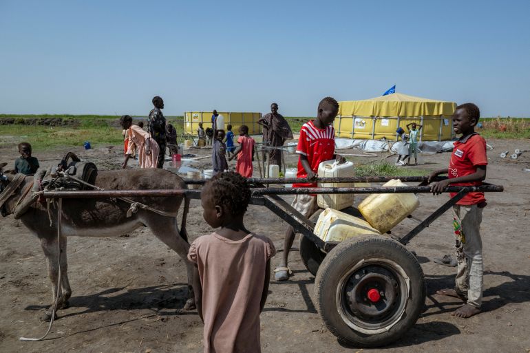 afp_69274ebf6654-1764183743 A donkey carries a makeshift cart loaded with plastic jerrycans as children fill it with water near the Joda-Wunthow border point in Renk County, Upper Nile, South Sudan, on November 15, 2025.